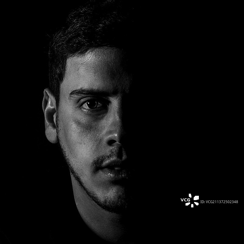 黑色背景下的年轻男子特写图片素材