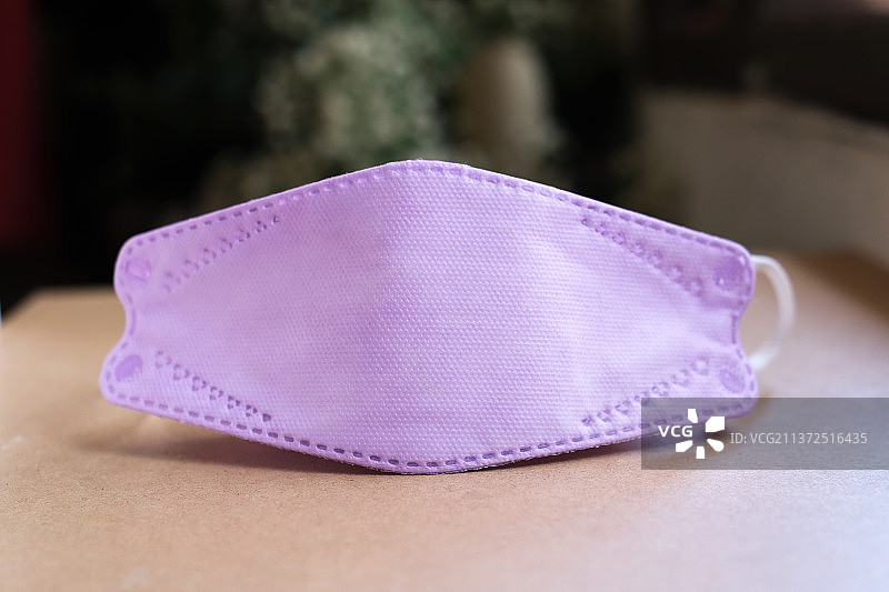 紫色防病毒口罩，桌子上粉色帽子的特写，印度尼西亚图片素材