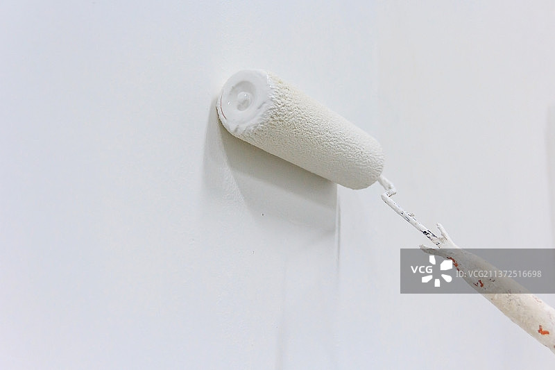 油漆工用滚筒粉刷墙壁的手臂特写图片素材