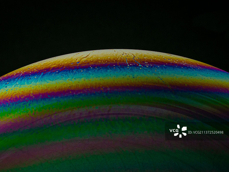 彩虹泡泡之美：黑色背景上的彩色特写图片素材