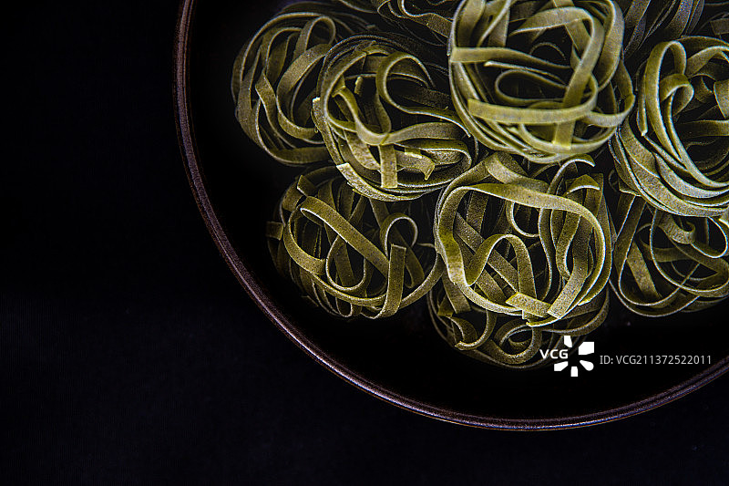 黑色背景碗中的绿色意大利面图片素材