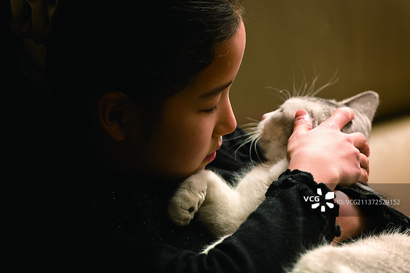 在沙发上拥抱可爱小猫的东方女孩图片素材