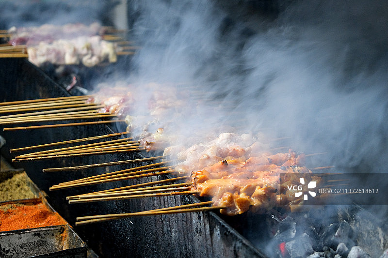 正在烤炉上烤羊肉串特写旁边放有调料图片素材