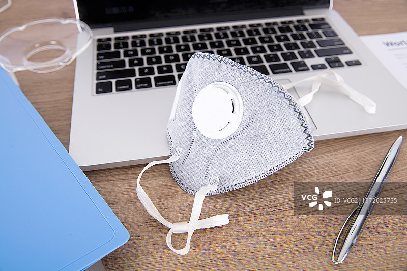 办公桌上笔记本电脑旁的N95口罩图片素材