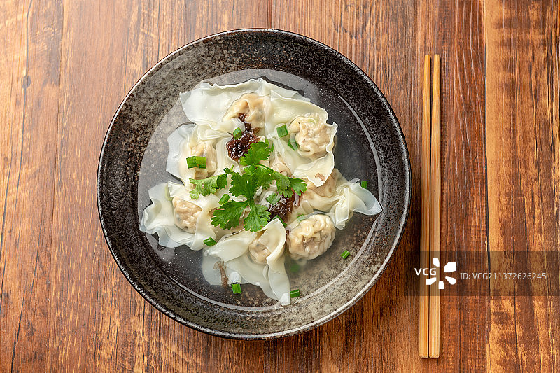 一碗馄饨和卤蛋拌黄瓜摆放在木桌面上图片素材