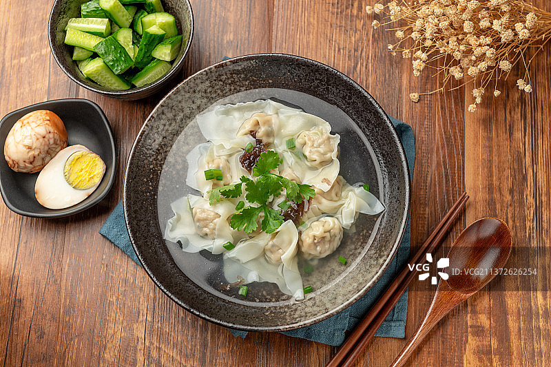 一碗馄饨和卤蛋拌黄瓜摆放在木桌面上图片素材
