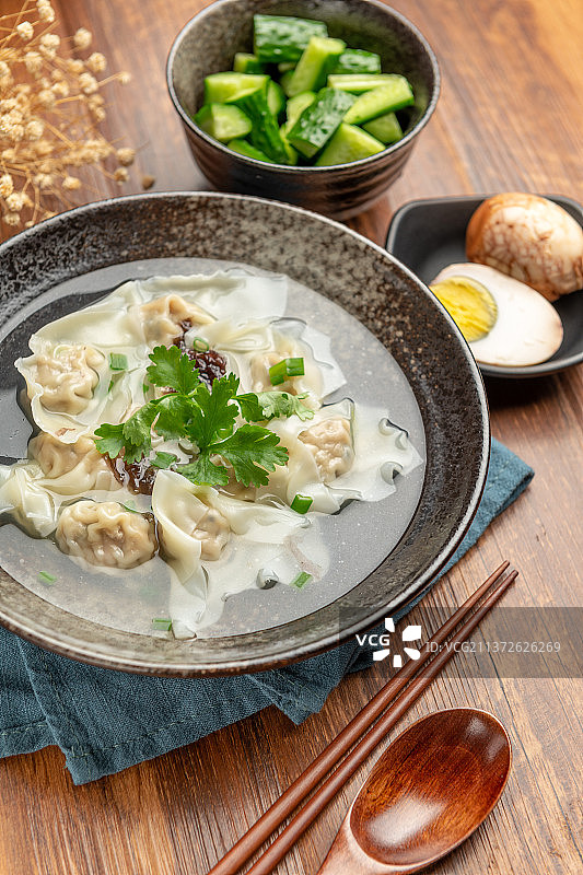 一碗馄饨和卤蛋拌黄瓜摆放在木桌面上图片素材