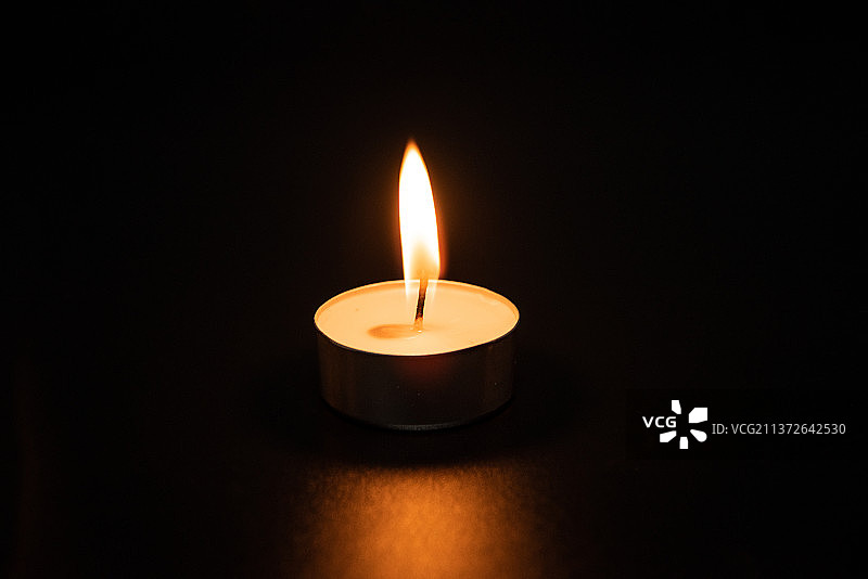 黑色背景上点燃的一支蜡烛图片素材