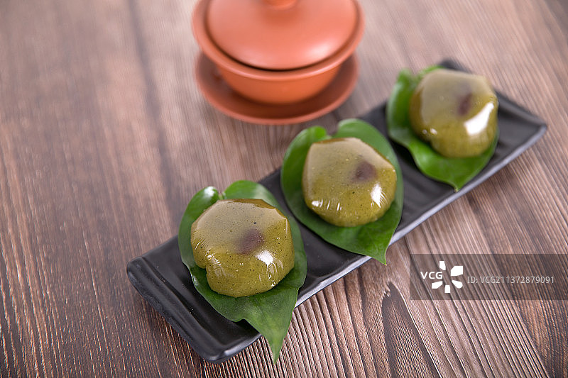 一盘清明节的食物糯米艾草青团子和一碗茶图片素材