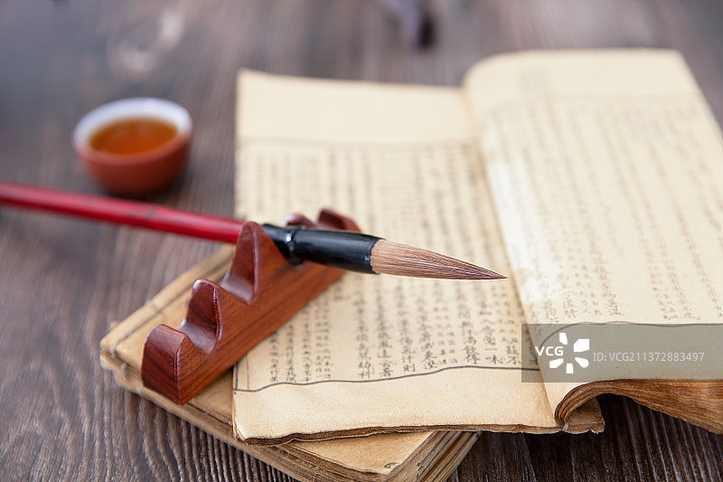 俯视桌子上的古旧书籍和毛笔及放在书上的一碗茶图片素材