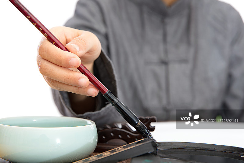 穿着唐装的书法家手拿毛笔在砚台里沾取墨汁图片素材