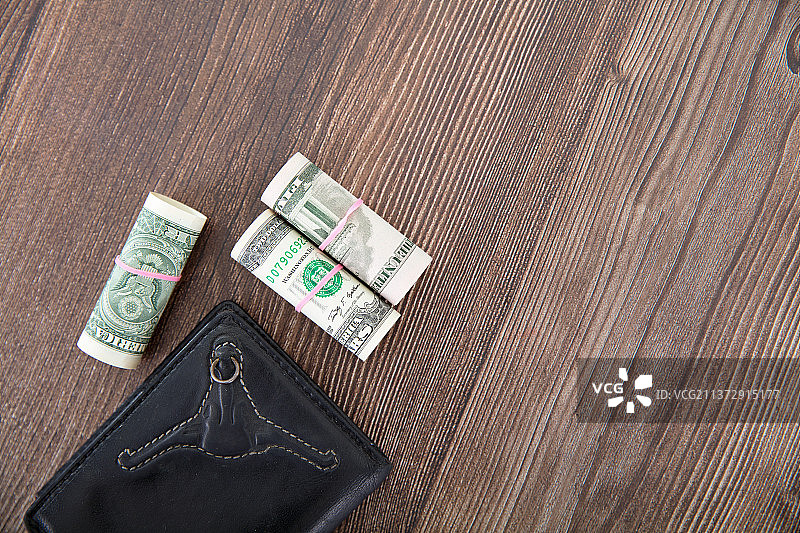 桌子上的钱包和卷筒状的美元钞票图片素材
