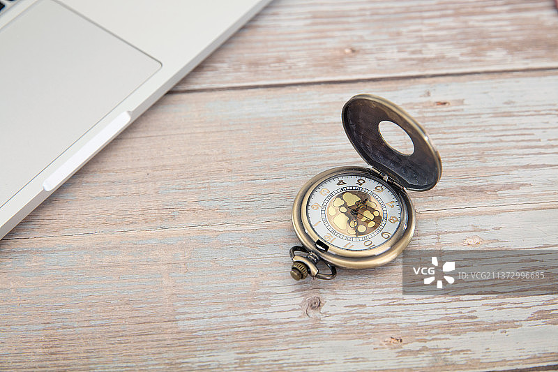 放在笔记本电脑旁边的怀表图片素材