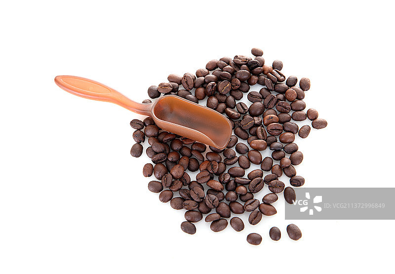 白背景上一堆摊开的咖啡豆和一把勺子图片素材