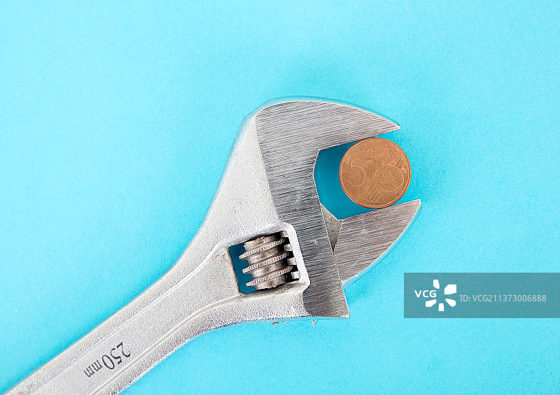 蓝色背景上一把活口钳子夹住一枚面值5分的欧元硬币图片素材