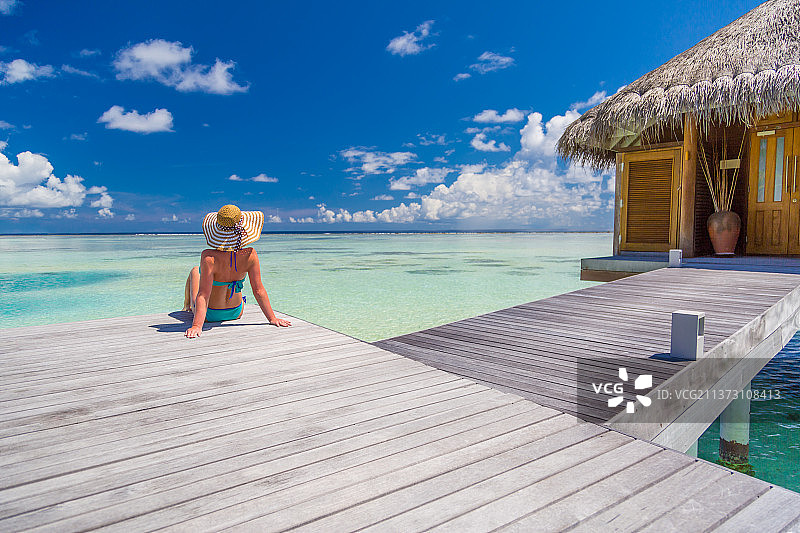 穿比基尼的女人站在马尔代夫迪胡菲诺鲁岛南环礁海边的码头上图片素材