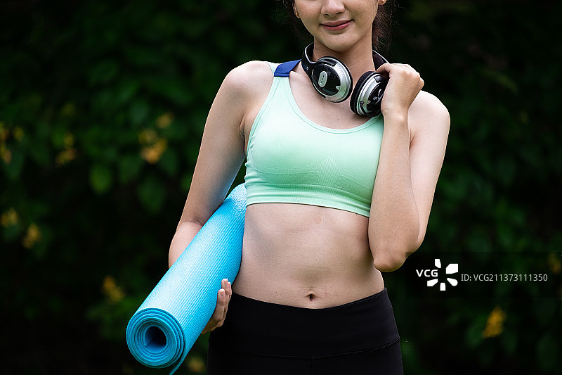 戴耳机 carrying 瑜伽垫的漂亮女孩图片素材