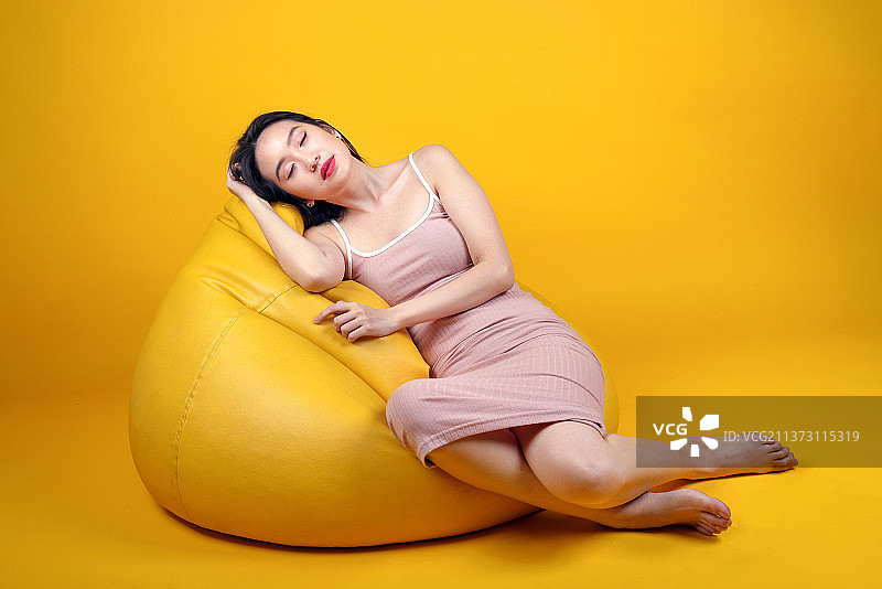 坐在黄色背景前的年轻女子肖像，马来西亚吉隆坡图片素材