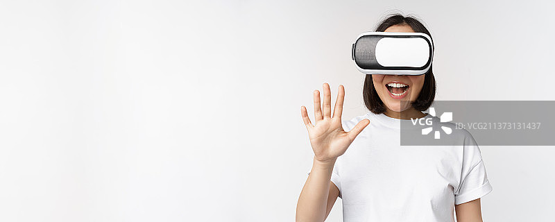 快乐的亚洲女人使用VR头显挥手欢笑图片素材