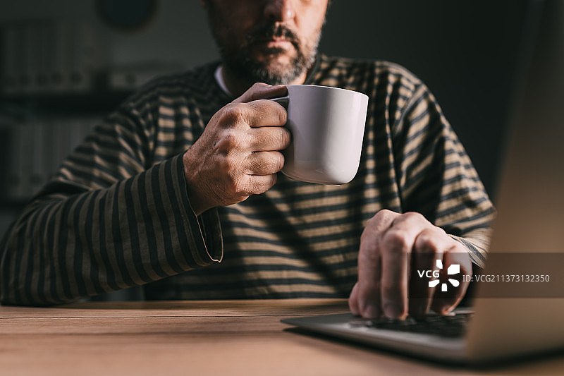 在塞尔维亚，用笔记本电脑工作的自由职业者，老年男子工作到很晚图片素材