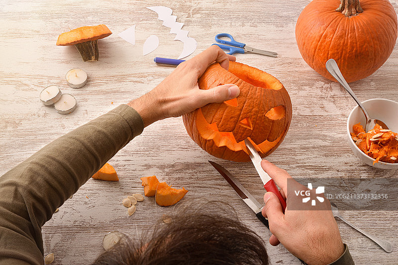 男子雕刻万圣节南瓜（俯视）图片素材