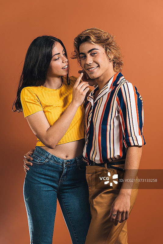 站在橙色背景下的年轻夫妇，西班牙图片素材