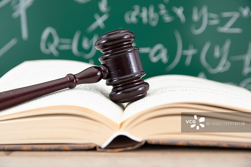 黑板前一本翻开的书和书上一个法锤图片素材