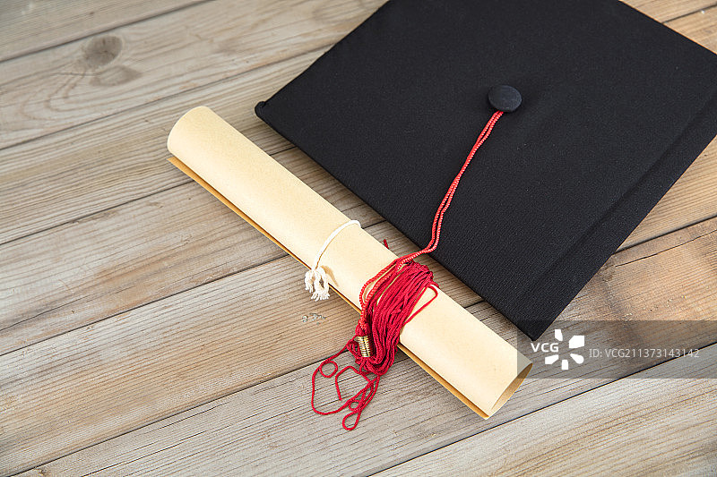 俯视桌子上的博士帽和卷着的毕业证书图片素材