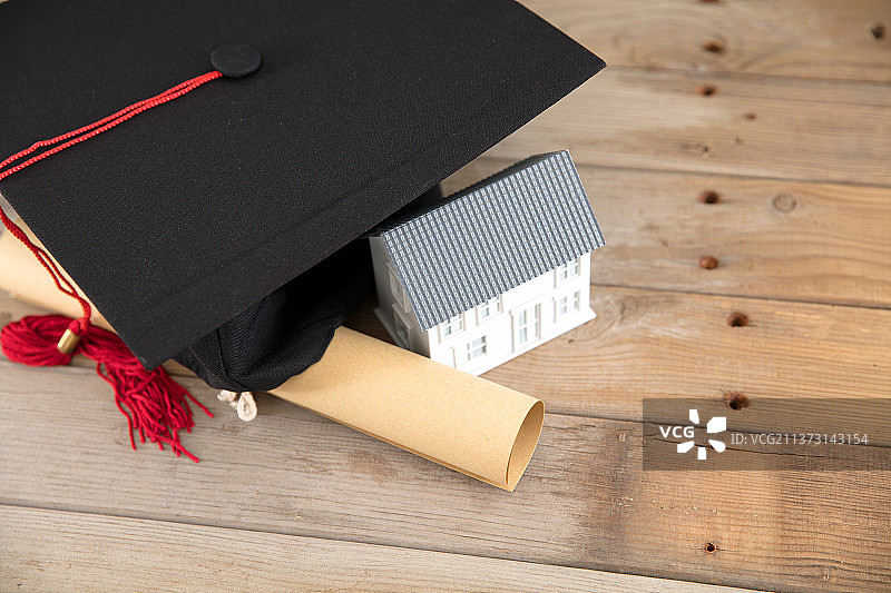 俯视桌子上的博士帽和毕业证书及小房子模型图片素材