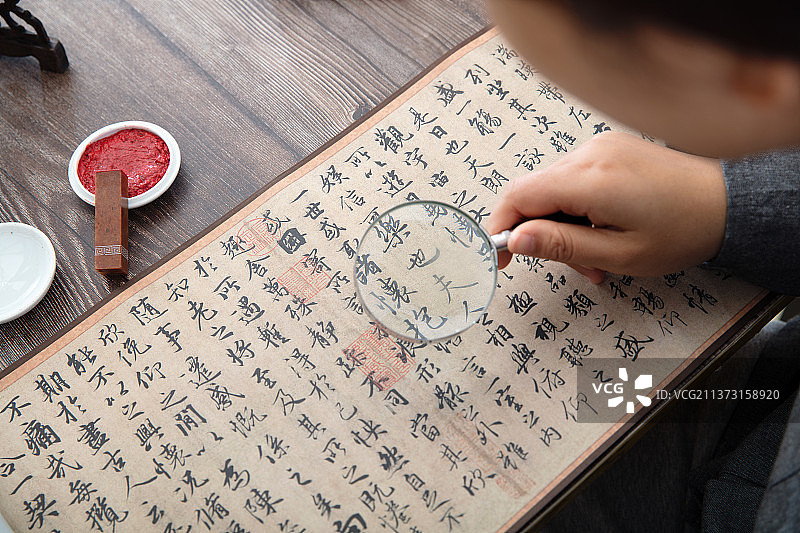 书法艺术家手持放大镜仔细欣赏王羲之的兰亭集序作品图片素材