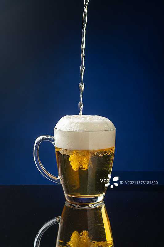 向杯中倒啤酒特写深色背景图片素材