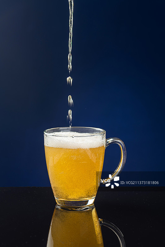 向杯中倒啤酒特写深色背景图片素材