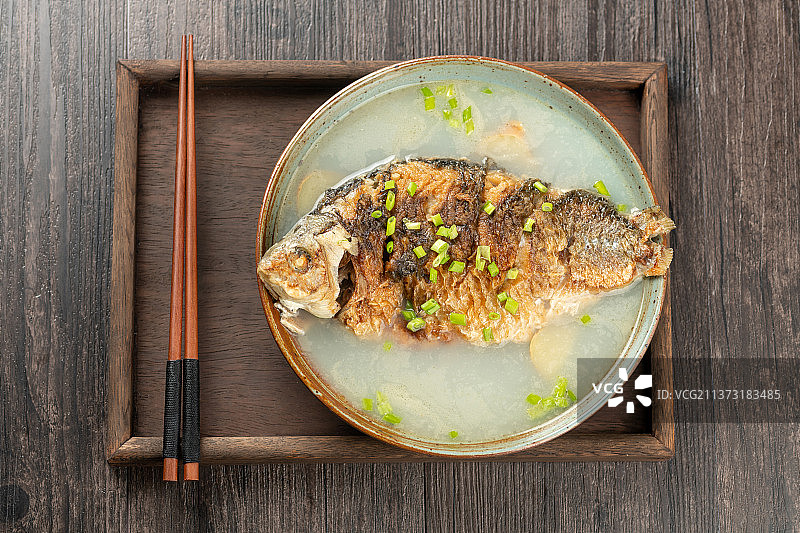 一盆鲫鱼汤摆放在木桌面上特写图片素材