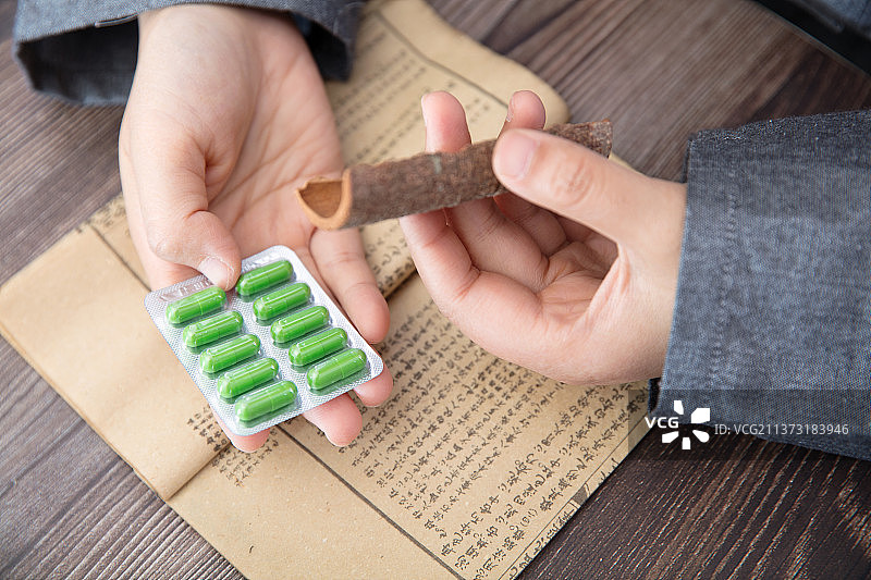 中医药师手拿成品中药胶囊和主要成分桂皮仔细对比图片素材