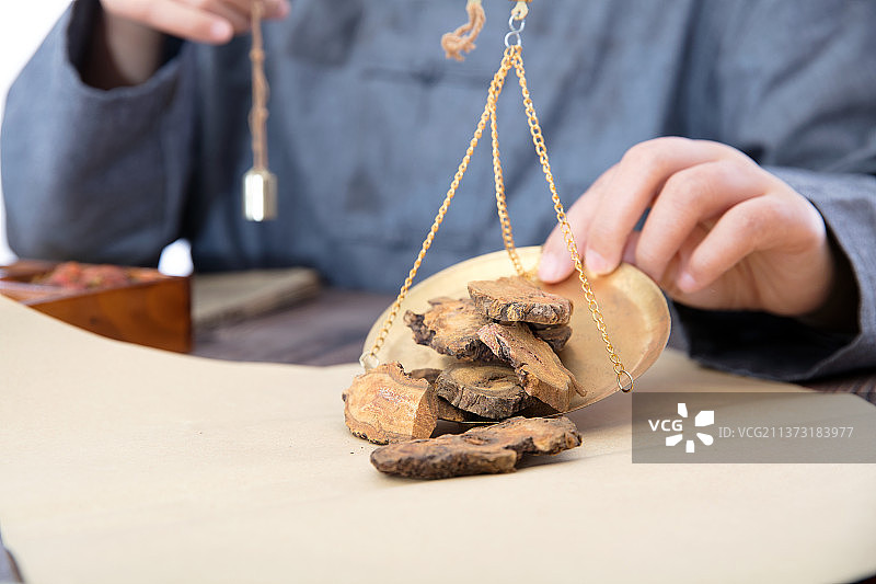 中医大夫把秤盘里的中药大黄倒在草纸上图片素材