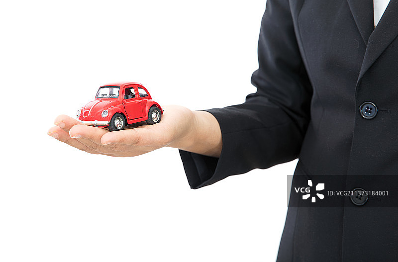 白背景前汽车销售人员手托小汽车模型图片素材