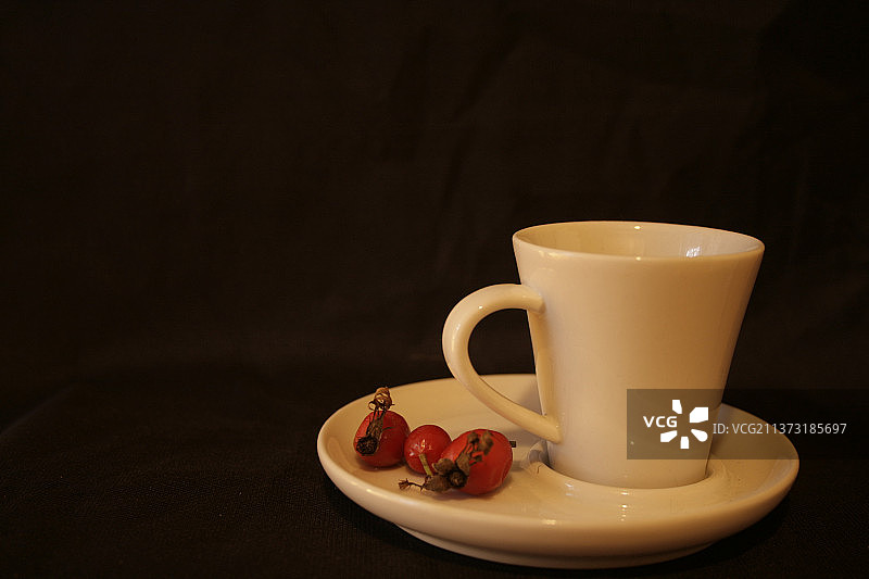 黑色背景下，桌子上放着带水果的咖啡杯特写图片素材