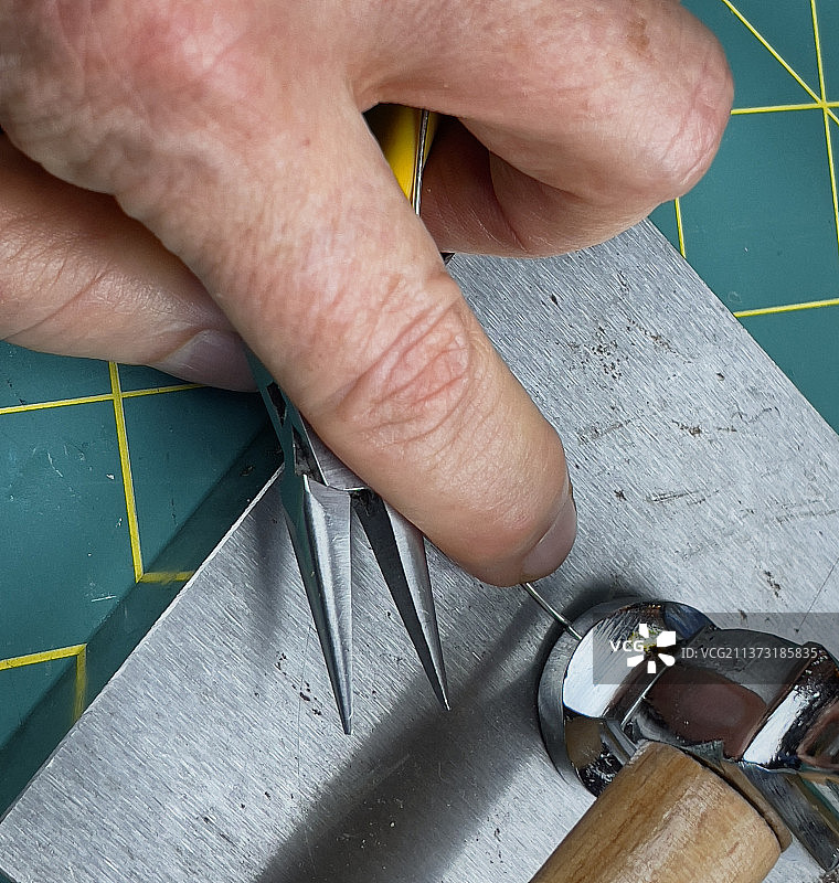 手指在钢块上用锤子握住银线特写图片素材