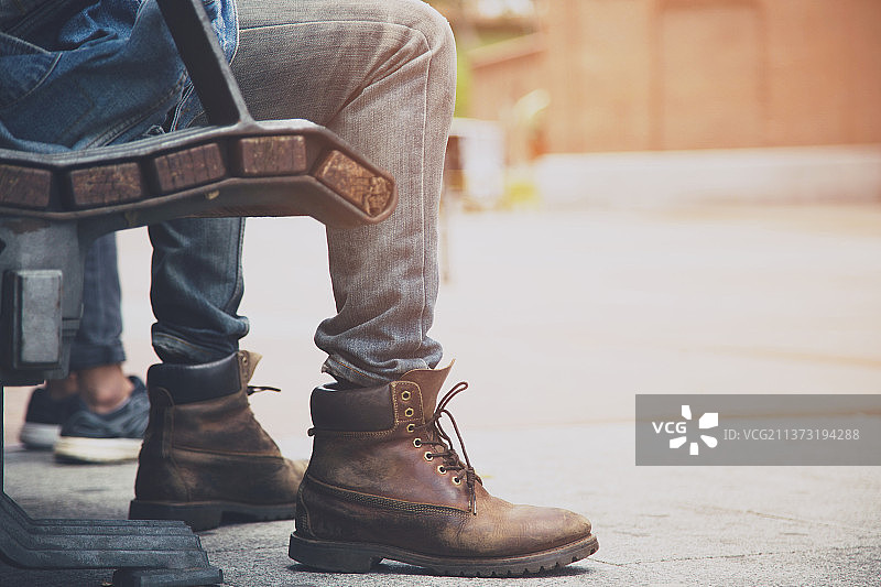 特写：运动鞋，坐在台阶上的男士（未识别，下半身）图片素材