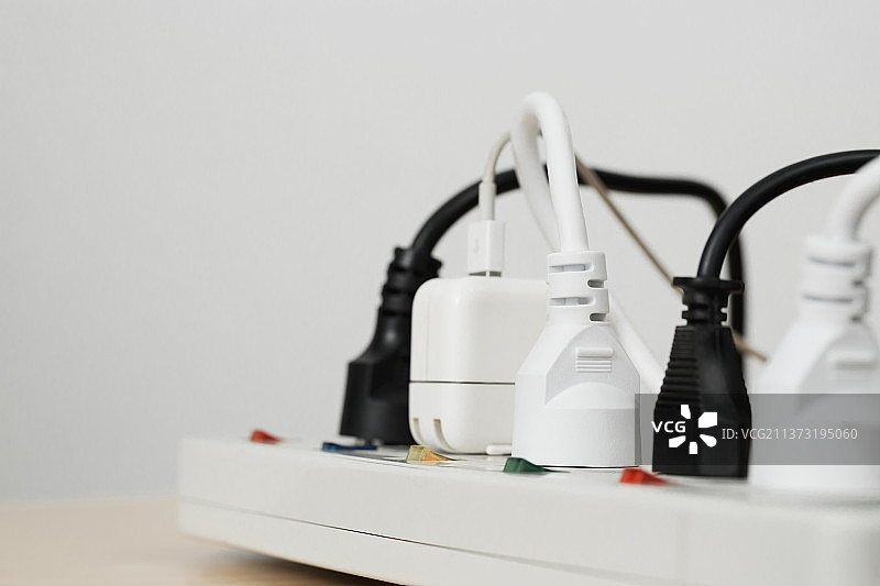 插满的电器插头，白色背景下桌上的电气设备特写图片素材