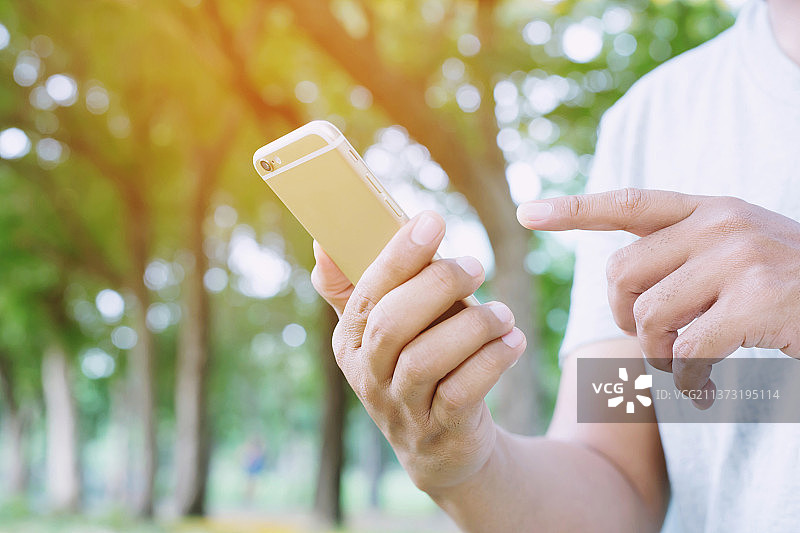 年轻男人穿格子衬衫，男人在树林里使用手机图片素材