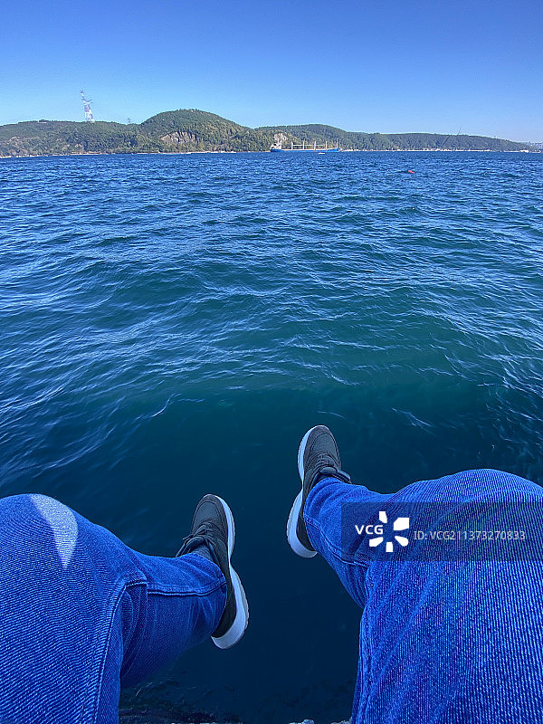 坐在船上，以大海为背景的男人下半身视角图片素材