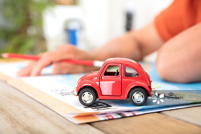 放在地图册上的小汽车模型和正在查看地图的人图片素材