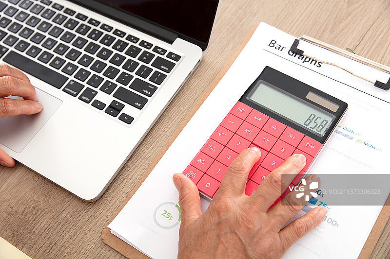 俯视拍摄女会计师正在使用计算器工作图片素材