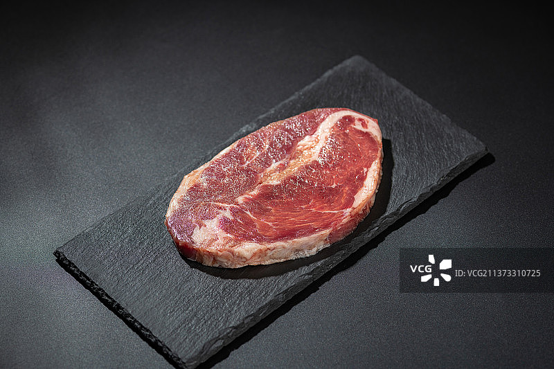 一块新鲜的牛排特写黑色水泥桌面背景图片素材