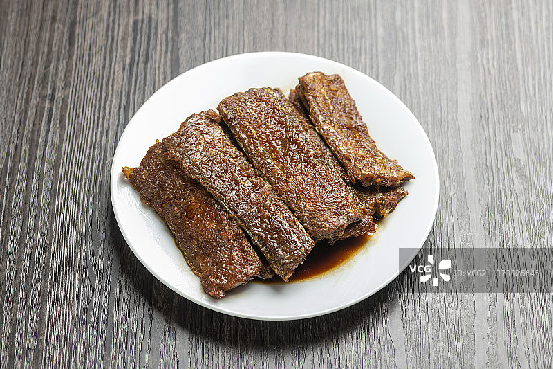 红烧带鱼摆放在木桌面上特写深色调图片素材