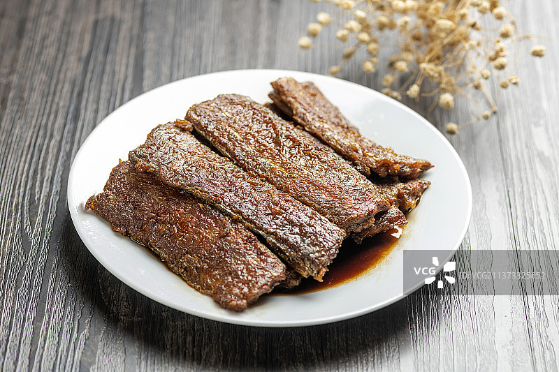 红烧带鱼摆放在木桌面上特写深色调图片素材