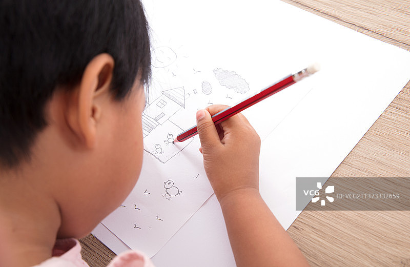 俯视拍摄中国小女孩趴在桌子上画画图片素材