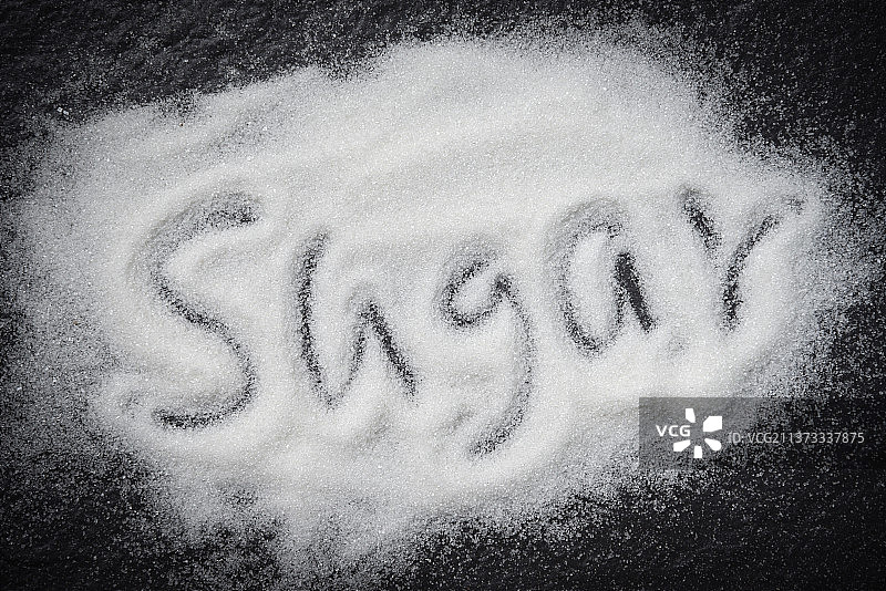 深色背景上的一堆白糖，文字为“糖”图片素材