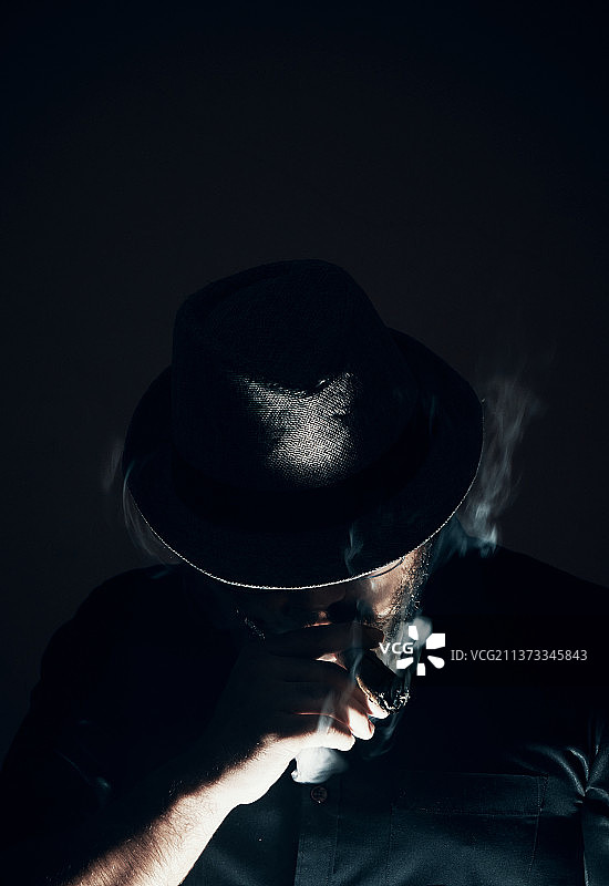 戴帽子抽雪茄的男人，黑色背景图片素材
